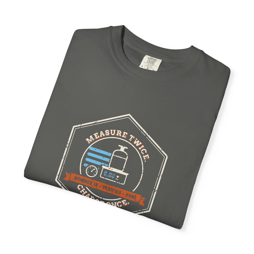 Folded Faded black t-shirt with a retro Measure Twice. Charge Once. hex badge with a cylinder on a scale