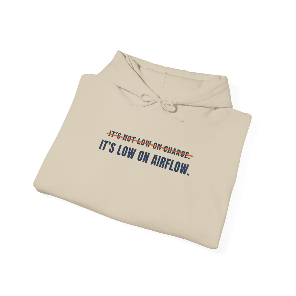 Folded sand hoodie reading It's Not Low on Charge, struck through, then It's Low on Airflow across the chest
