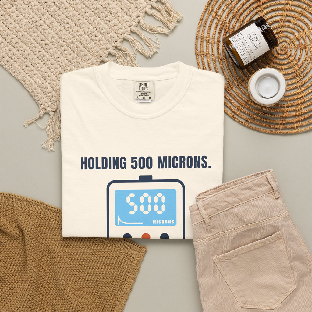 Folded ivory t-shirt reading Holding 500 Microns. Unlike My Patience. with a vacuum gauge graphic