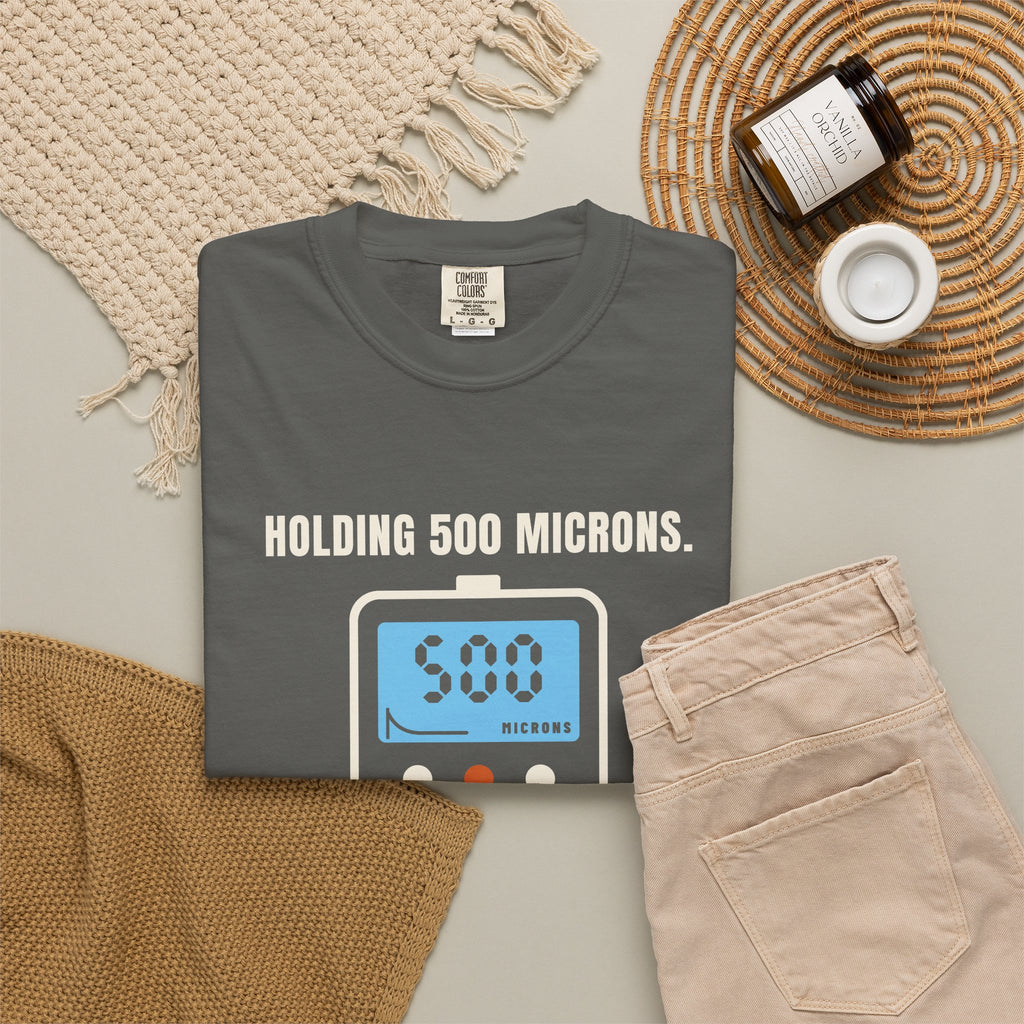 Folded faded black t-shirt reading Holding 500 Microns. Unlike My Patience. with a vacuum gauge graphic