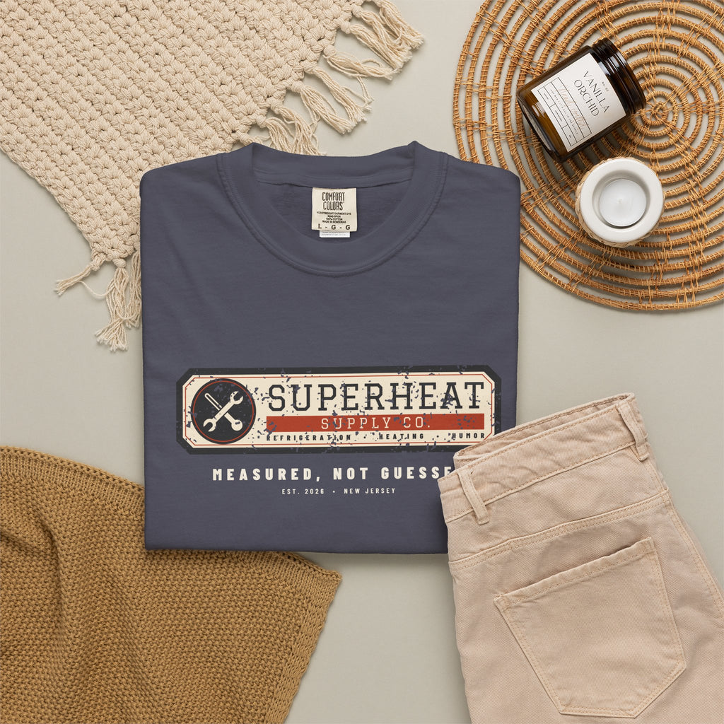 Folded navy t-shirt with a vintage equipment data plate reading Superheat Supply Co., Refrigeration Heating Humor