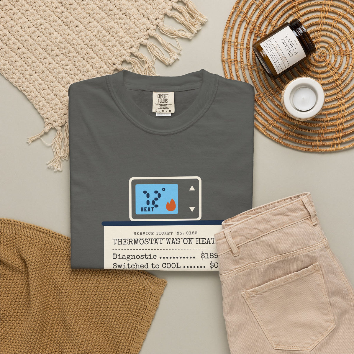 Folded faded black t-shirt reading Thermostat Was on Heat. Diagnosis: $189. with a simple thermostat graphic