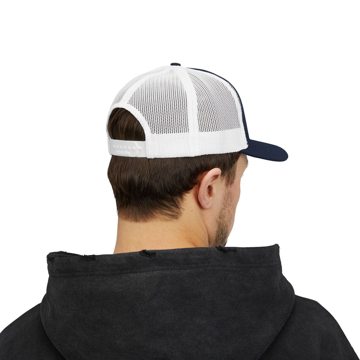 Person wearing the navy and white trucker hat, seen from the back with white mesh panels and a snapback