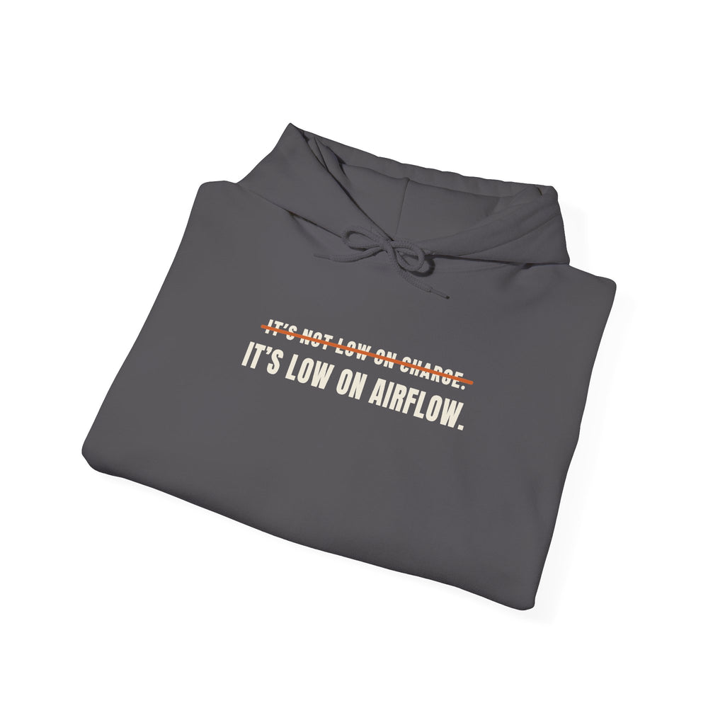 Folded charcoal hoodie reading It's Not Low on Charge, struck through, then It's Low on Airflow across the chest