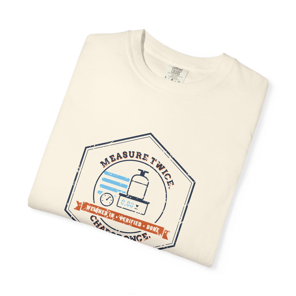 Folded Ivory t-shirt with a retro Measure Twice. Charge Once. hex badge with a cylinder on a scale
