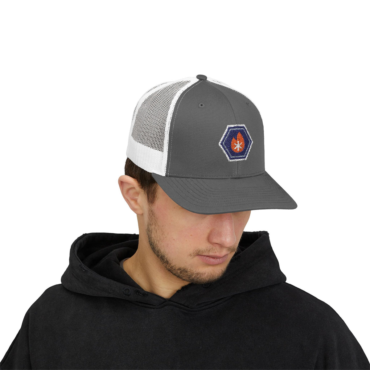 Person wearing a charcoal and white trucker hat with an embroidered fire-and-ice hex nut logo